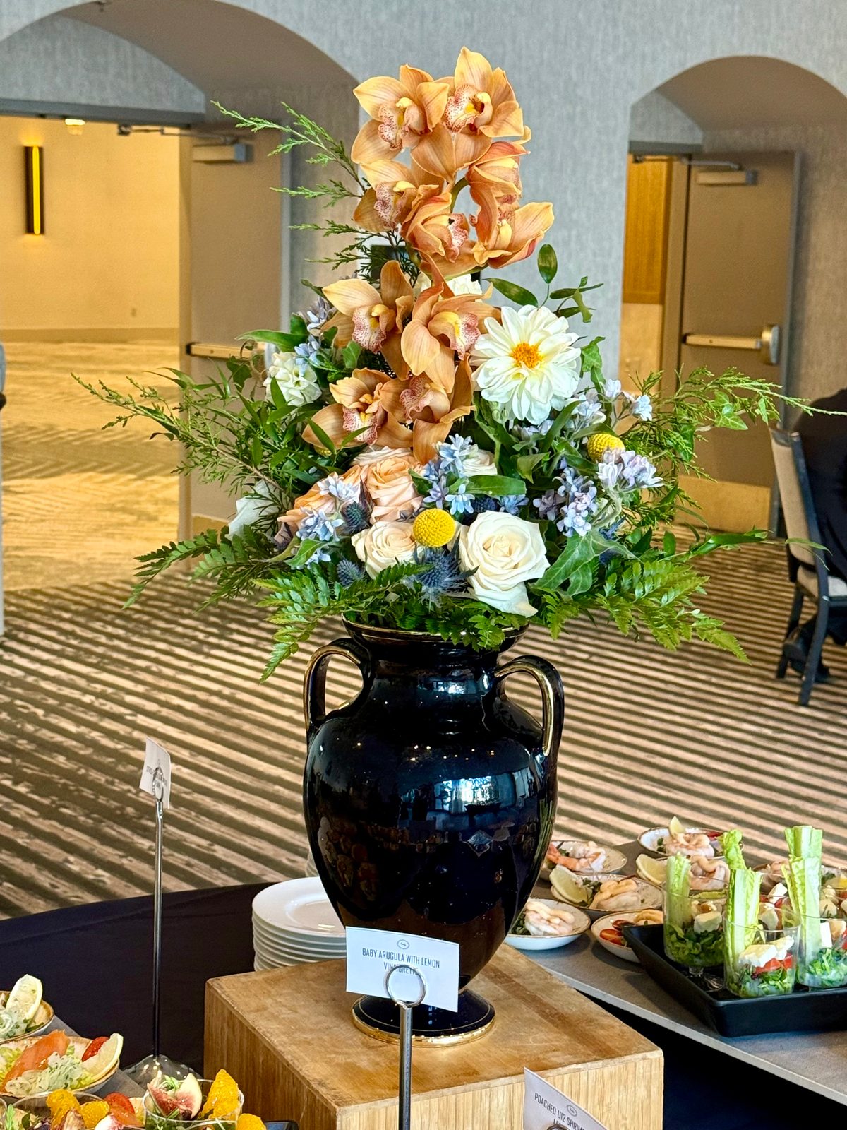 Grand orchid arrangement in dark urn for event